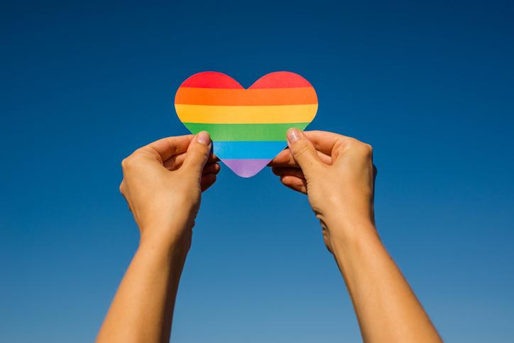 Two hands holding a rainbow heart