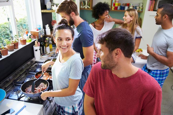 group of roommates in the kitchen cooking