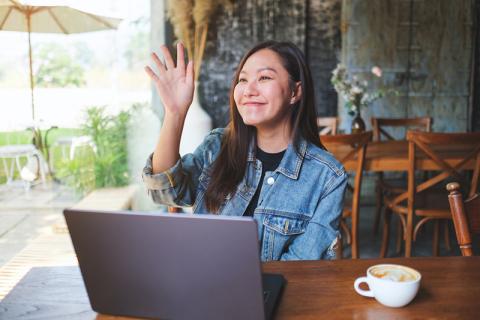 Young Asian woman greeting friend at cafe