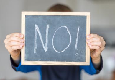 Student holds up mini blackboard, with the word "No!" on it